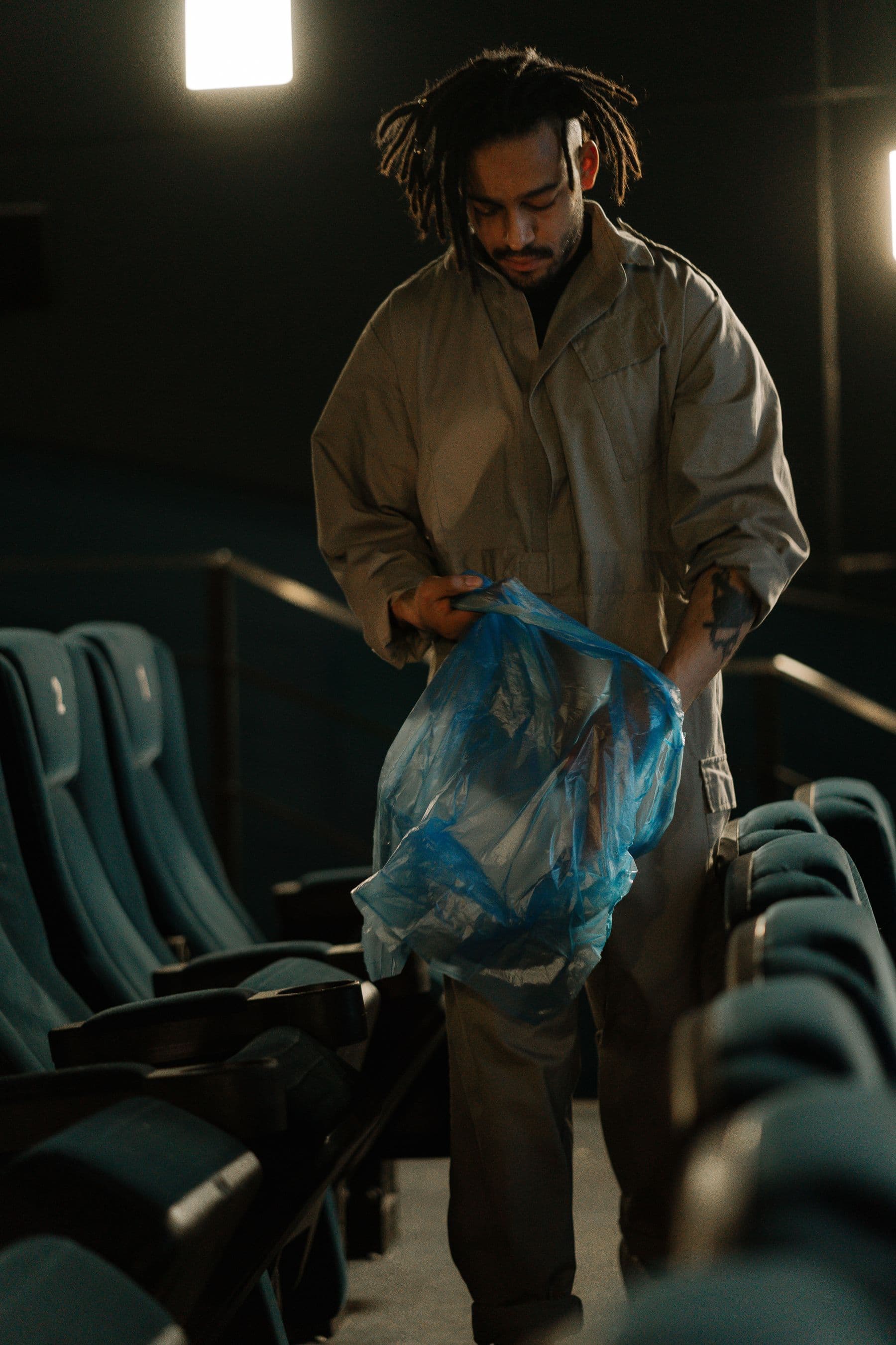 Cleaning professional collecting waste between rows of cinema seats