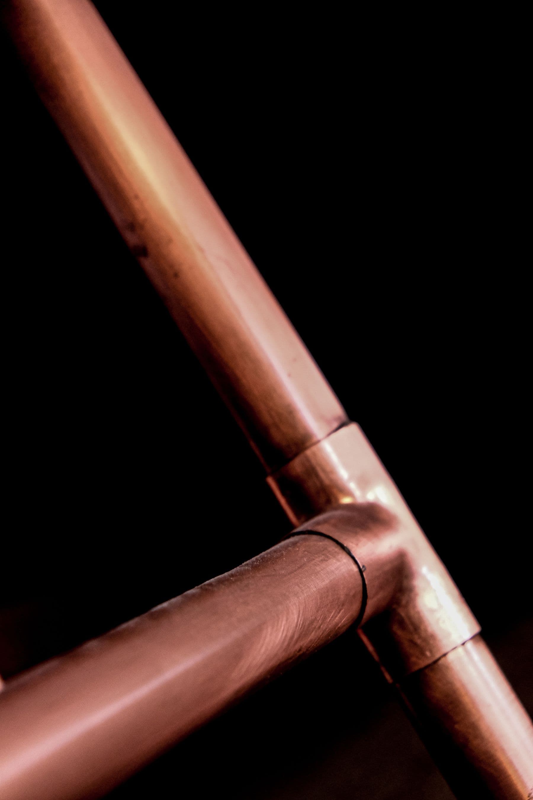 Close-up photograph of copper plumbing pipes and a joined fitting