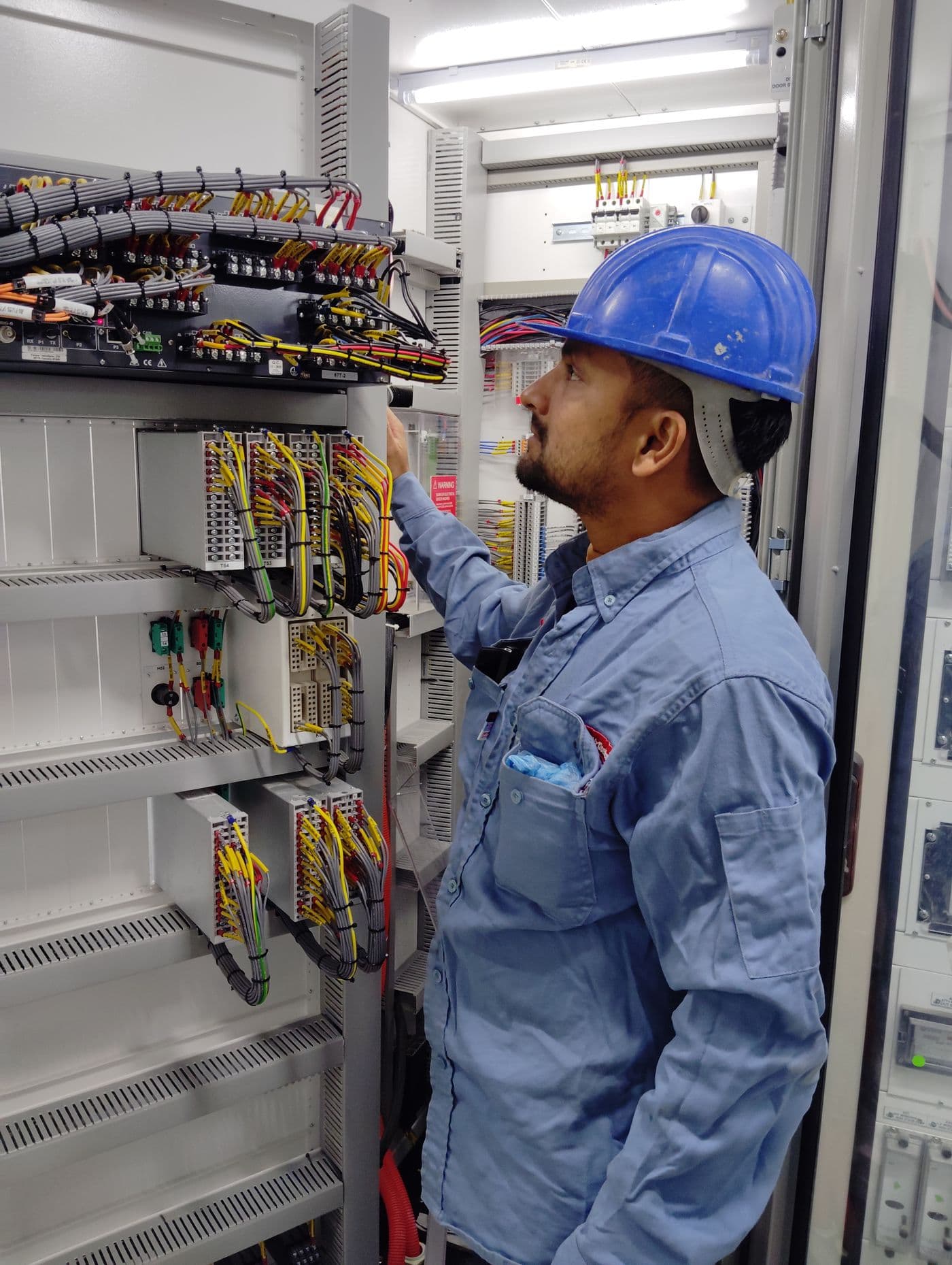 An electrician working at a control panel
