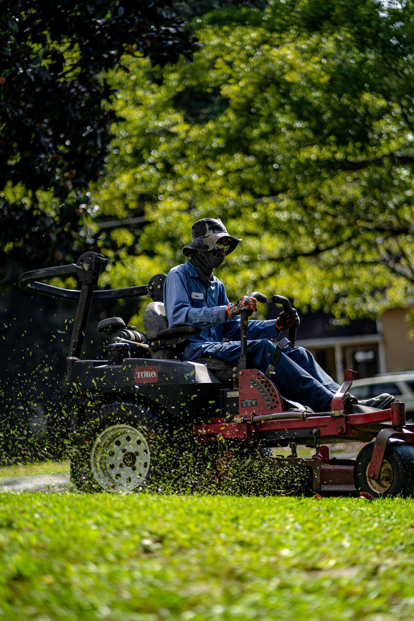 A groundskeeper mowing grass on a sunny day