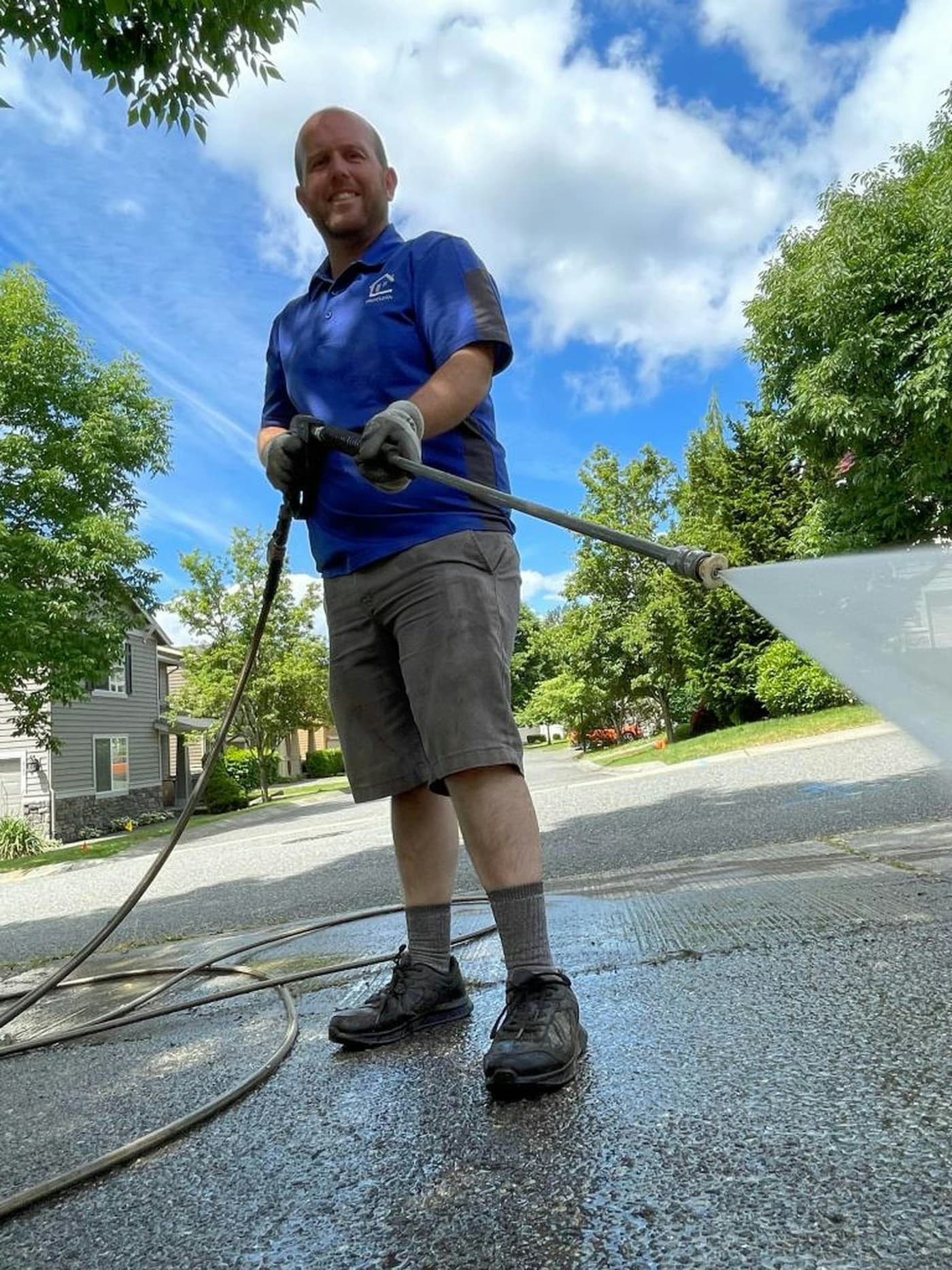 An exterior cleaner pressure washing a driveway